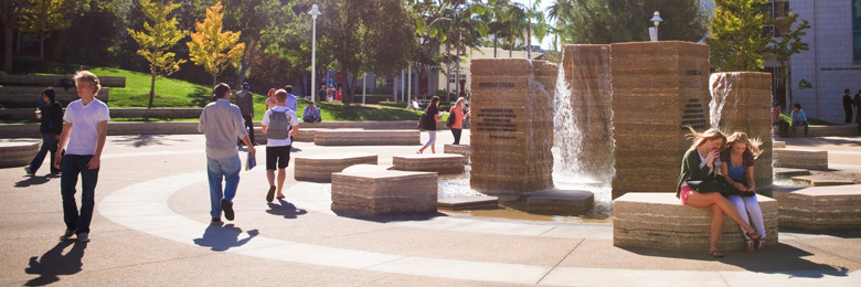 Student walking in Attallah Piazza at Chapman University