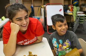 A student working with an elementary aged student.