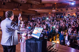 Audience and presenter holding candles at Disability Summit