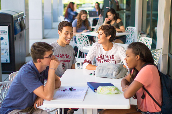 Students engage in a discussion at a table area on campus.