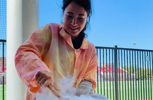 A student wearing a tie-dye lab coat performing an experiment outside