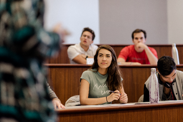 Chapman University students sit in a classroom, listening to a professor speak.