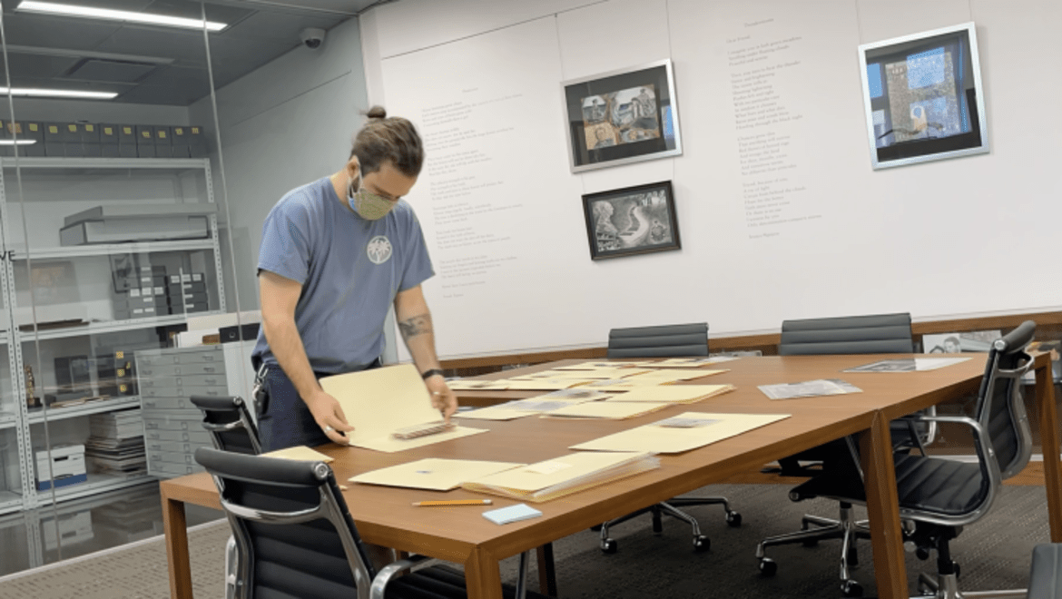 Will Hoskin works on the Szneer collection, examining folders full of archival documents on an office desk.