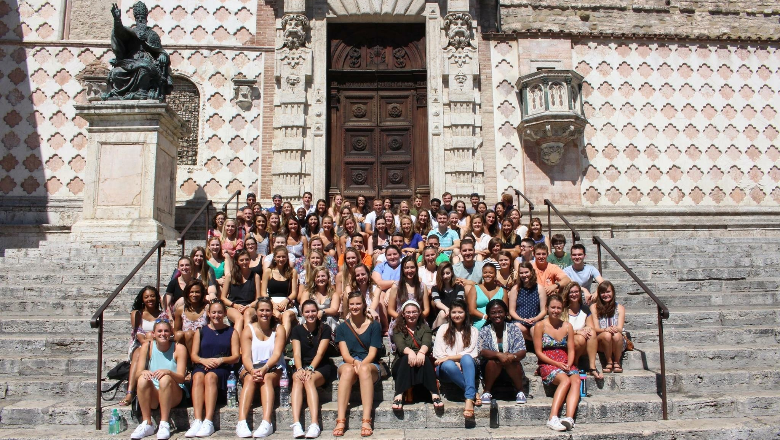 Group of students sitting on steps in front of building landmark in Europe