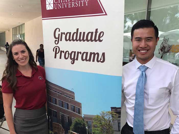 Graduate admission staff standing next to a sign that says graduate programs 