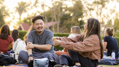 Students having a conversation while sitting on a lawn in the Chapman campus.