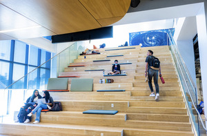Students studying and relaxing on a wide and brightly lit staircase.