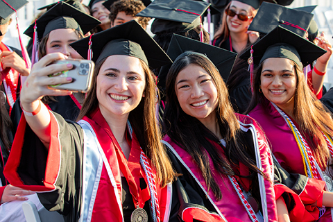 Chapman alumni posing for a picture in front of a step-and-repeat holding up a banner that reads "Chapman University Panthers."