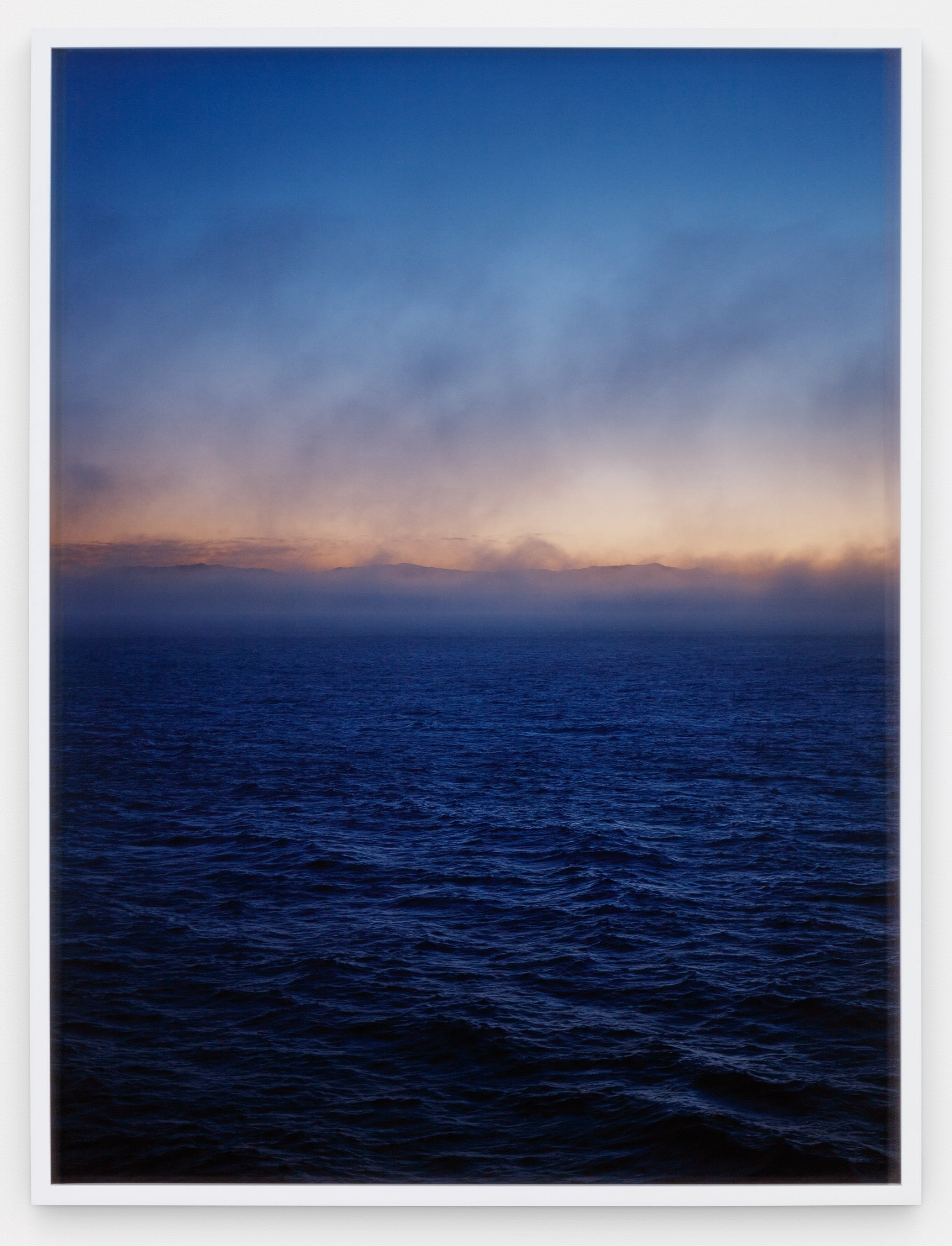 Photograph of the ocean with a pink sunrise.