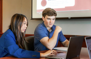 Students looking at a laptop in a conference room.