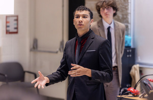Students giving a presentation at the front of a classroom. They are wearing professional attire.