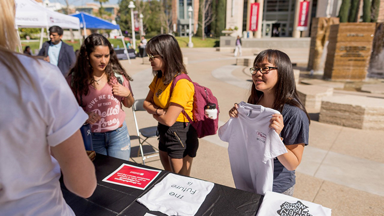 Student holding t-shirt at information fair