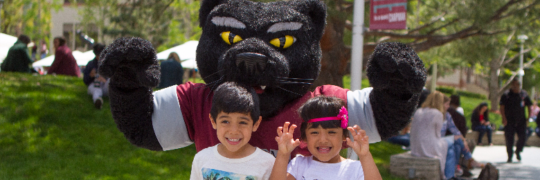 Young children stand in front of Pete the Panther on Chapman University's campus