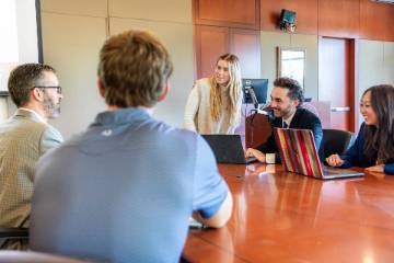A meeting room with people chatting around a table