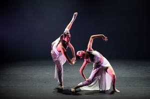 Two students dancing on stage, striking poses with their arms and legs bent.