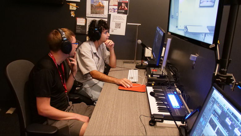 Two students working on a computer in a recording studio.
