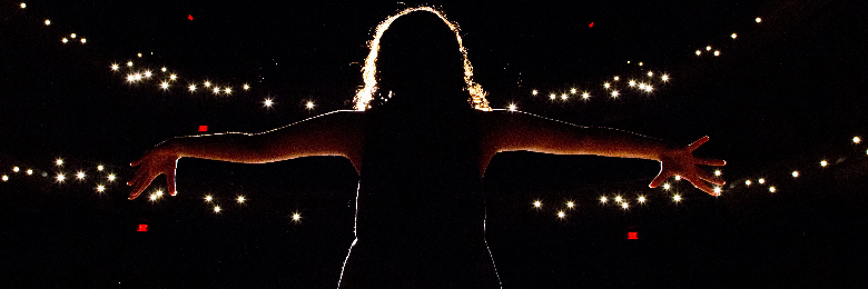 performer silhouetted against lights in Musco Center