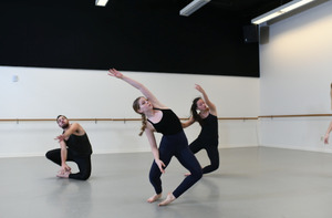 Three students practice in a dance studio.