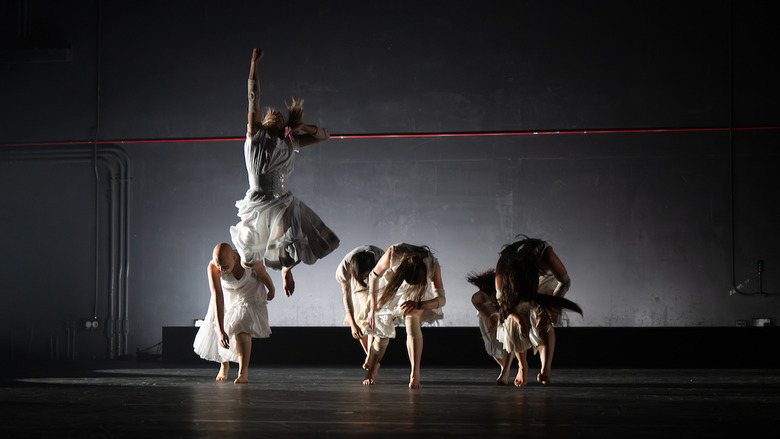 Several students dancing on a dark stage.