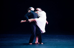 Two students dance on a dark stage.