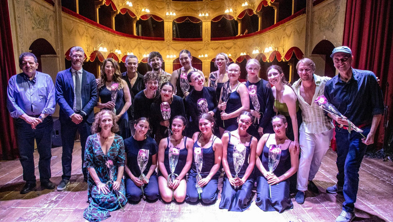 A group of dance students and faculty posing for a picture on a stage in Italy.