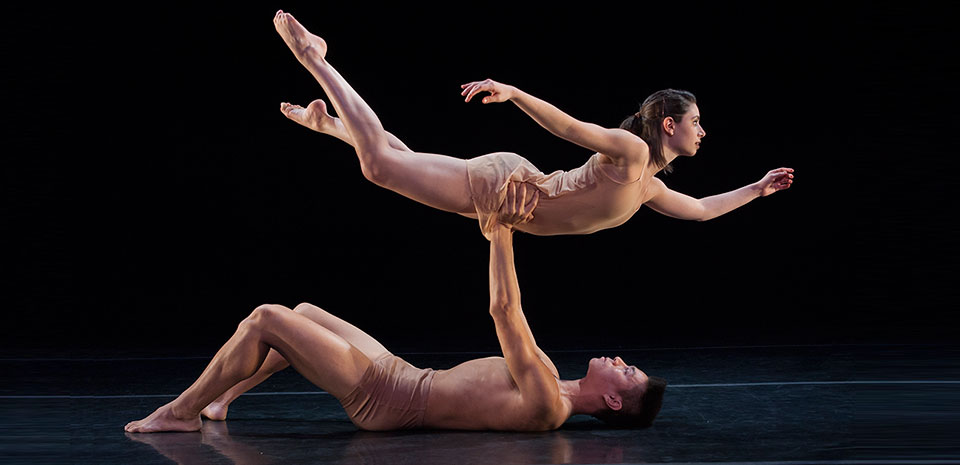 male dancer on his back lifting a female dancer above him in horizontal position
