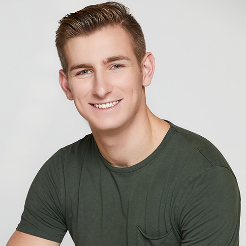 Smiling young man with crew-cut hair in green t-shirt.