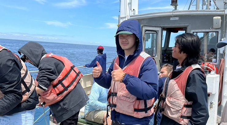 Chapman alum on research boat in Maine giving a thumbs up