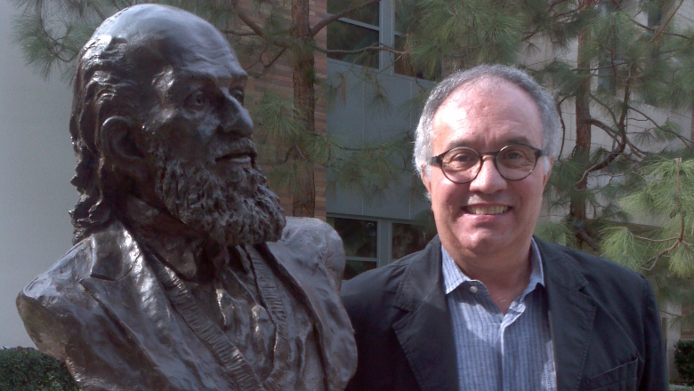 Man standing next to bust of Paulo Freire on the Chapman campus