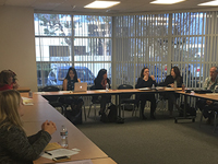 Group of people sitting at u-shaped desk in a meeting