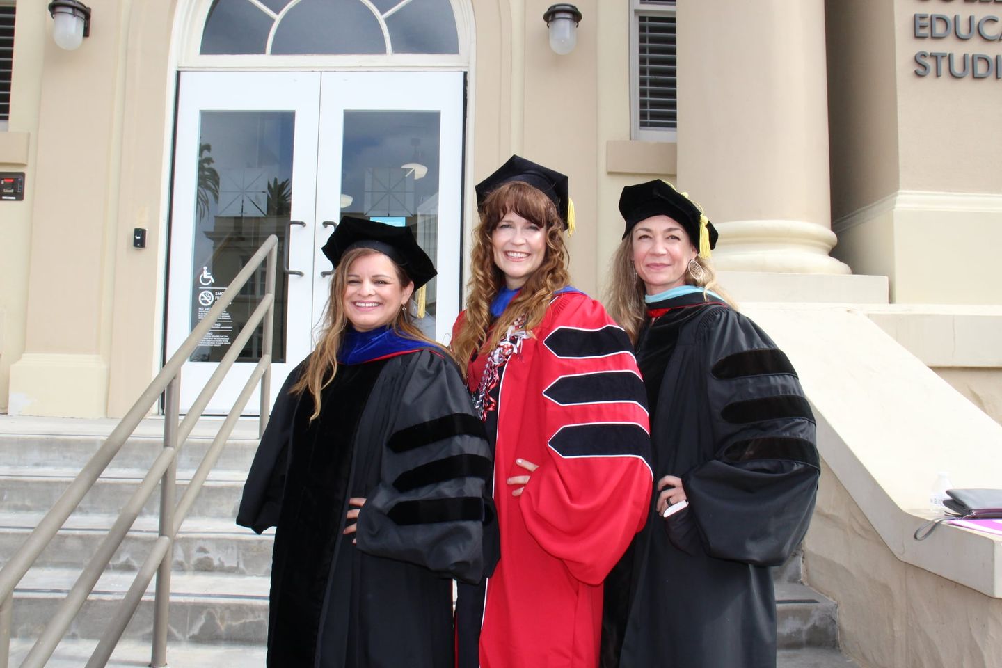 Audri Sandoval Gomez (TPI's Associate Director), Jennifer James (TPI's Office Manager and Special Project Coordinator), and Meghan Cosier (TPI's Director) posing in front of Reeves Hall at Chapman University