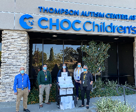 Staff at CHOC posing in front of Thompson Autism Center with donated iPads