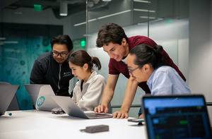 Students working on laptops in a study room.