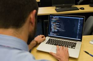 A student writes code on a laptop.