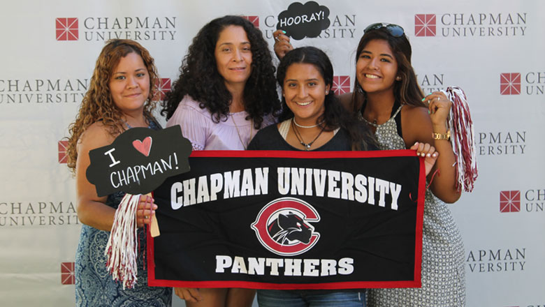 four woman holding chapman university signs and apparel