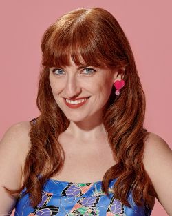Pink background. A woman with red long hair and a blue dress.