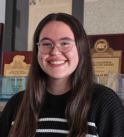 Woman wiht brown hair and glasses and a black and white sweater