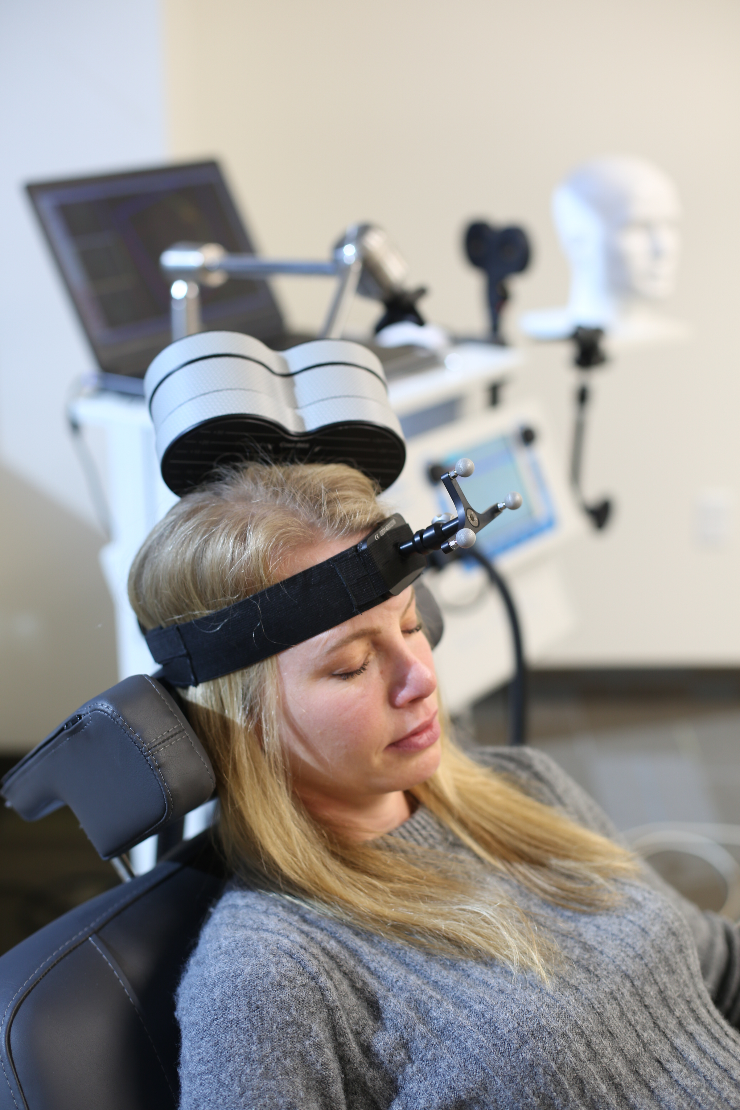 Research subject in chair with TMS wand near head.