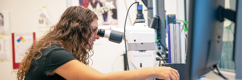 student looking into microscope