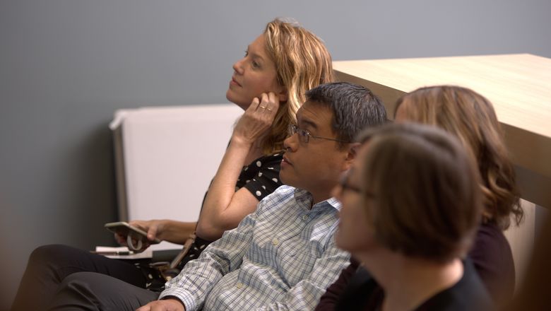 Four students sit in a row in a classroom, paying close attention to the lesson.