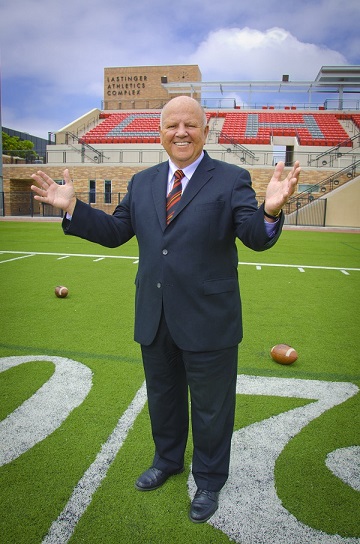 Dave Currey in a suit standing on football field