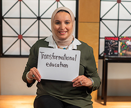woman holding a sign that says "transformational education"