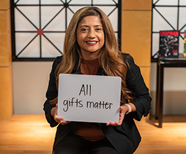 woman holding a sign that says "all gifts matter"