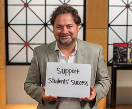 man holding a sign that says "support students success"