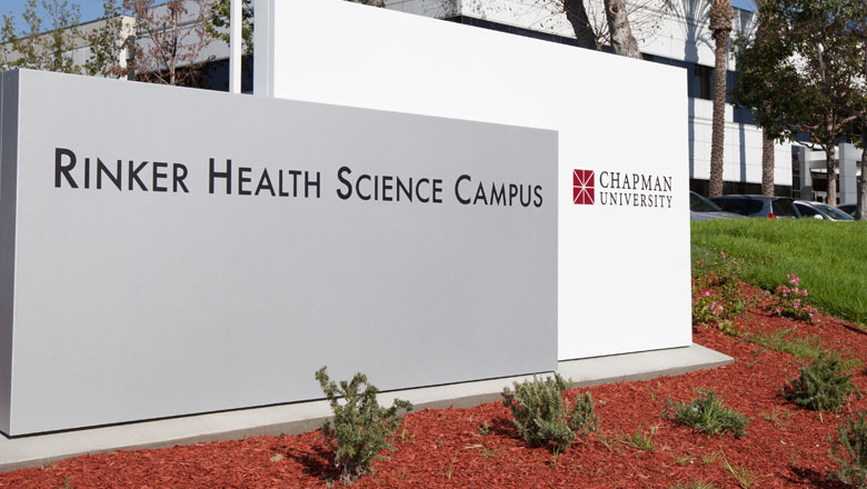 sign that says rinker health science campus chapman university sitting in red ground and grass
